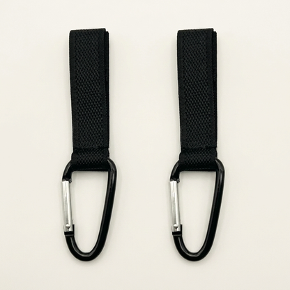 Two black webbing straps with carabiners on a light beige background