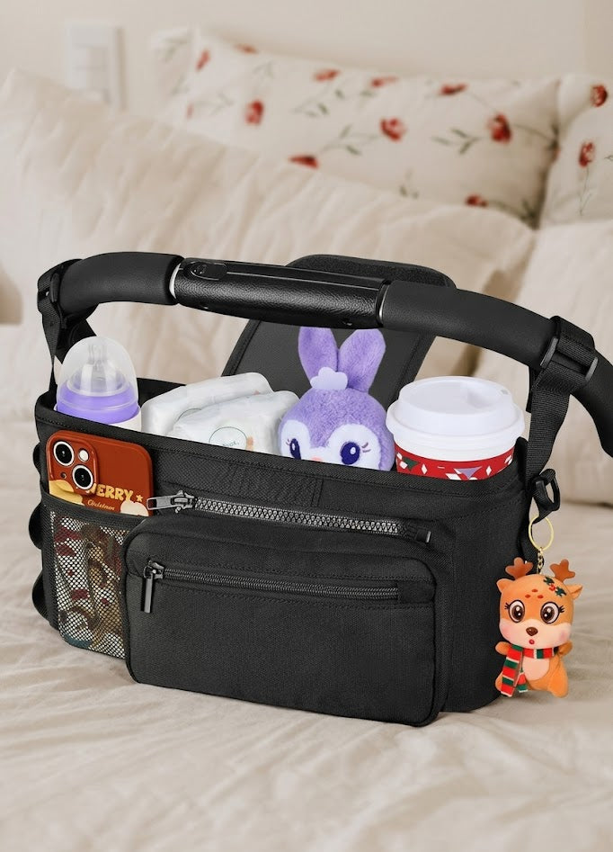 Black diaper bag with baby items on a bed